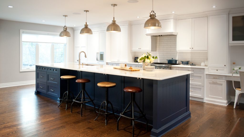 Colchester Drive kitchen with white cabinetry, a navy island and brass pendants